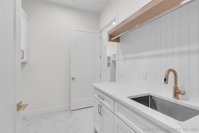 kitchen with sink, white cabinetry, light stone counters, and light tile patterned floors