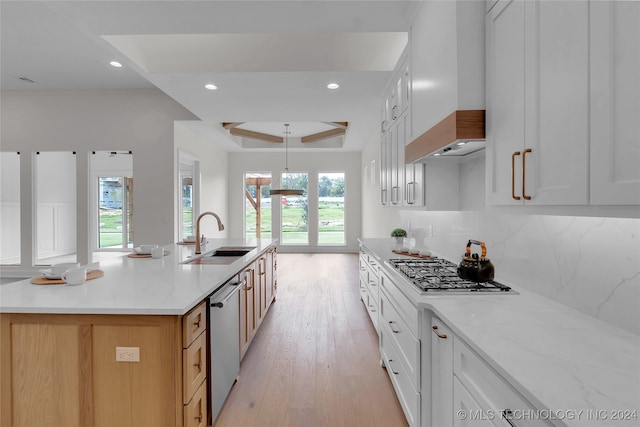 kitchen featuring sink, light wood-type flooring, custom exhaust hood, an island with sink, and white cabinetry