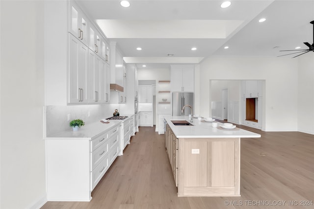 kitchen with ceiling fan, light hardwood / wood-style flooring, a center island with sink, and white cabinets