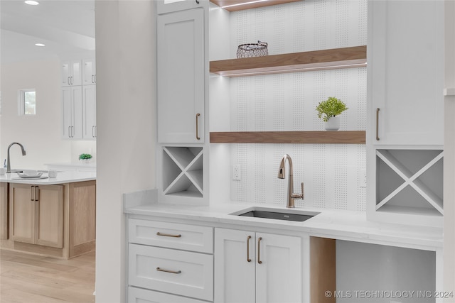 interior space with sink, light hardwood / wood-style flooring, white cabinetry, and light stone countertops