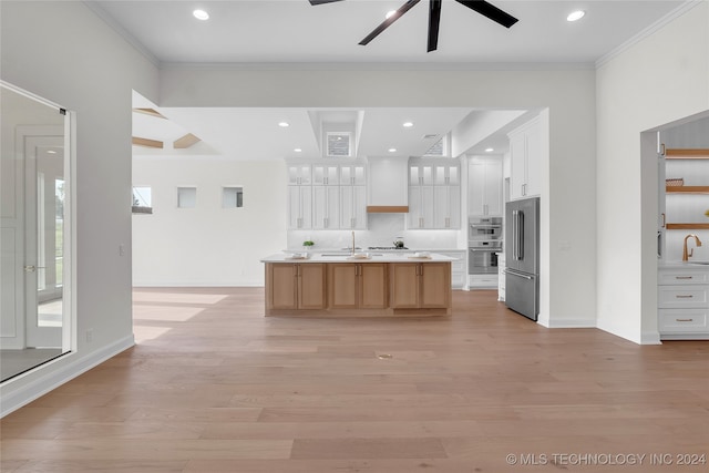 kitchen with ceiling fan, a kitchen island with sink, white cabinetry, and light wood-type flooring