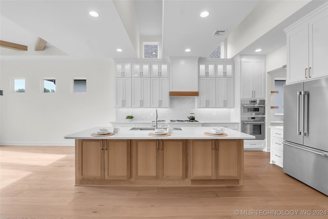 kitchen featuring sink, an island with sink, light hardwood / wood-style floors, stainless steel appliances, and white cabinets