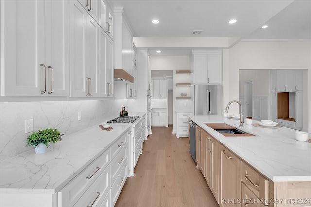 kitchen featuring light hardwood / wood-style flooring, light stone counters, decorative backsplash, stainless steel appliances, and white cabinets