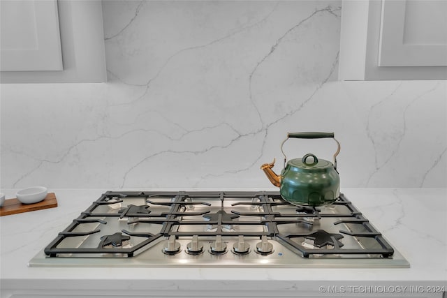 interior details with white cabinetry, backsplash, and stainless steel gas cooktop