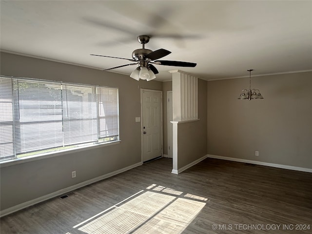 empty room with a wealth of natural light, ceiling fan with notable chandelier, ornamental molding, and wood-type flooring