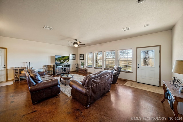 living area featuring visible vents, a textured ceiling, and baseboards