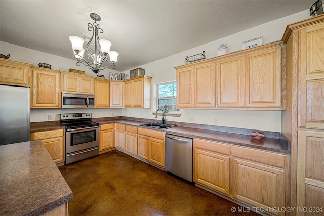 kitchen with dark countertops, appliances with stainless steel finishes, a sink, and hanging light fixtures