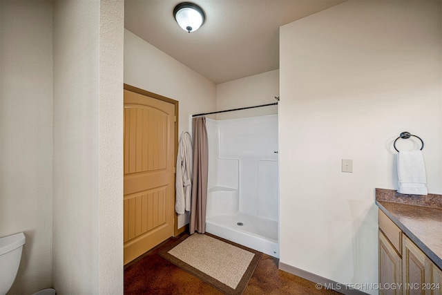 bathroom with a stall shower, baseboards, vanity, and toilet