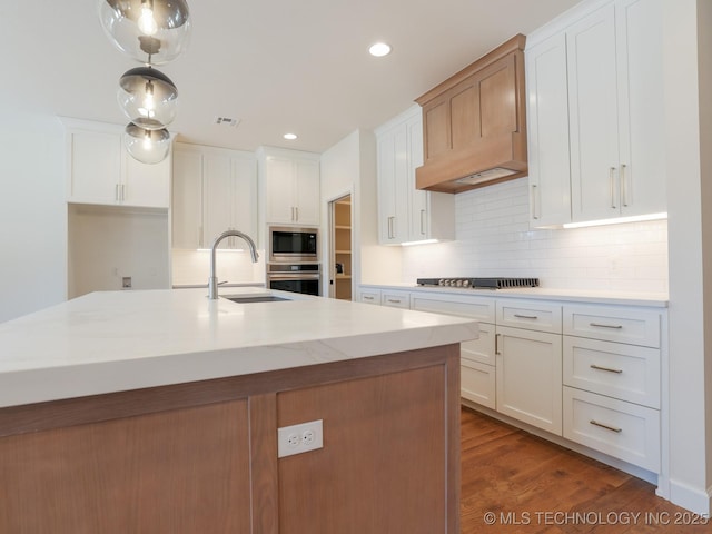 kitchen featuring stainless steel appliances, wood finished floors, a sink, visible vents, and backsplash