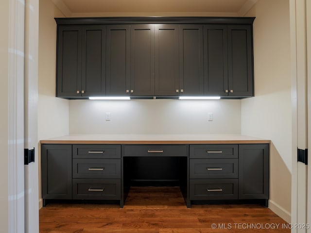 unfurnished office featuring built in desk and dark wood-type flooring