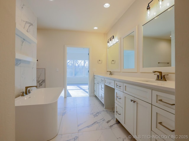 bathroom with double vanity, marble finish floor, a sink, and a soaking tub