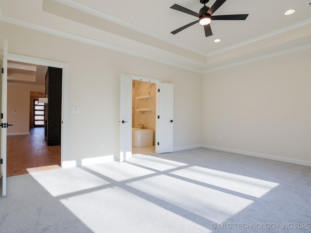 unfurnished bedroom featuring a tray ceiling, carpet flooring, crown molding, and baseboards