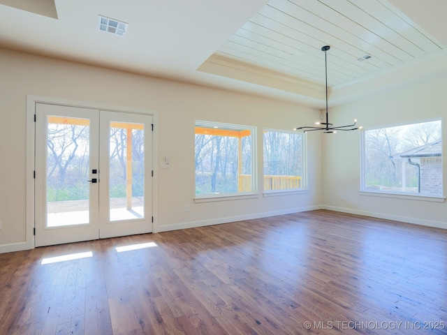 interior space featuring a tray ceiling, french doors, plenty of natural light, and wood finished floors