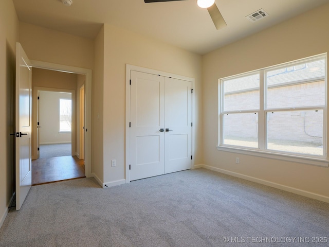 unfurnished bedroom with ceiling fan, light carpet, visible vents, baseboards, and a closet