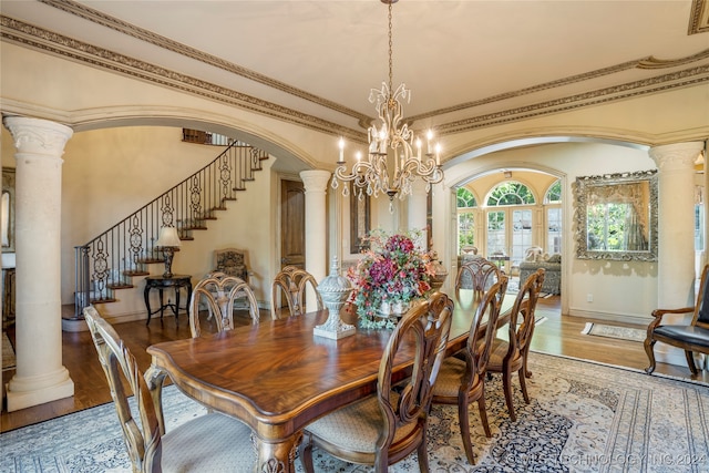 dining area featuring crown molding, a chandelier, decorative columns, and hardwood / wood-style flooring