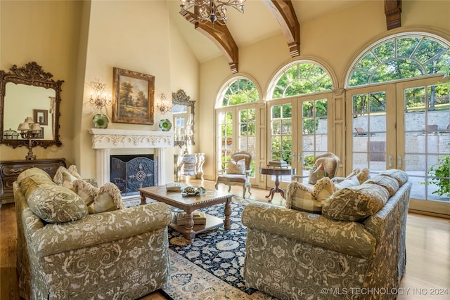 interior space with a towering ceiling, light hardwood / wood-style flooring, beamed ceiling, and a chandelier