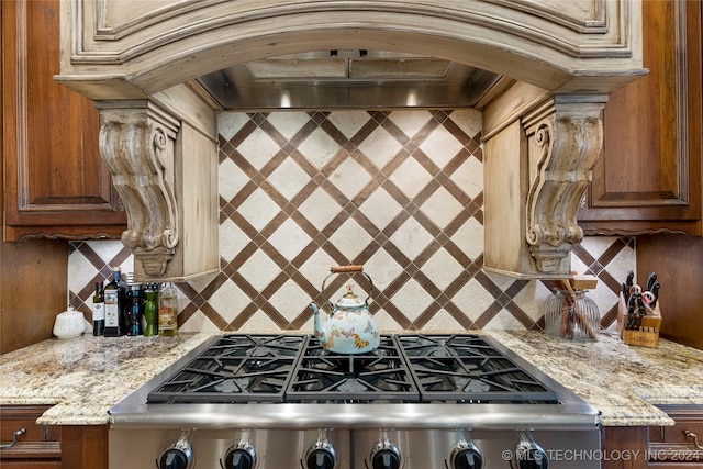 kitchen featuring decorative backsplash, ornamental molding, light stone counters, stainless steel gas stovetop, and custom exhaust hood