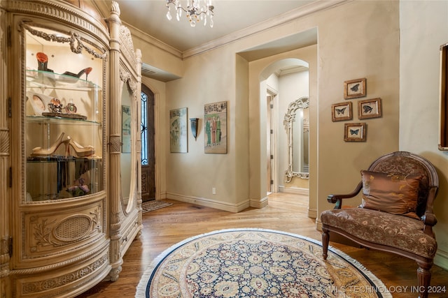 interior space with light hardwood / wood-style floors, ornamental molding, and an inviting chandelier