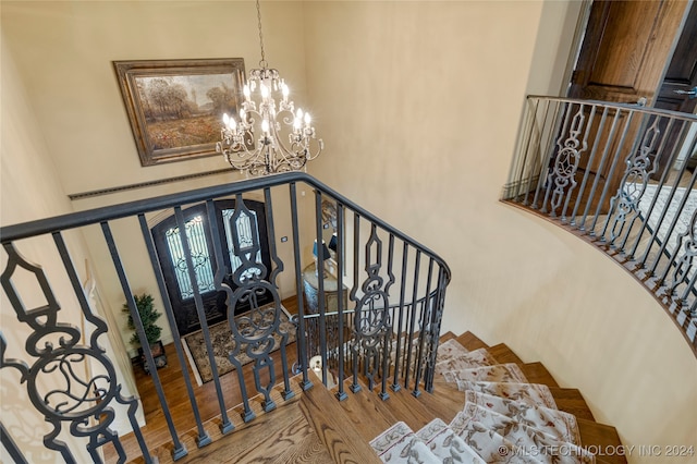 stairs with a high ceiling, a notable chandelier, hardwood / wood-style flooring, and french doors