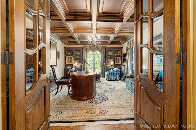 interior space featuring hardwood / wood-style floors, an inviting chandelier, ornamental molding, coffered ceiling, and beamed ceiling