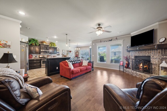 living room with ceiling fan, light wood-type flooring, a fireplace, and ornamental molding