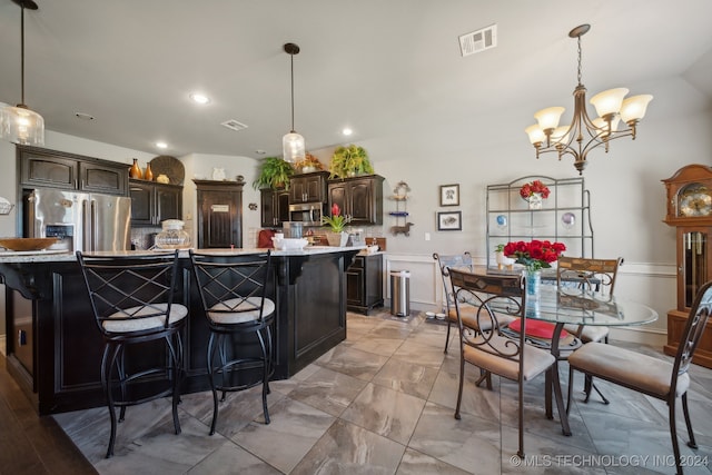 kitchen featuring stainless steel appliances, a large island, a kitchen bar, dark brown cabinetry, and light tile patterned floors