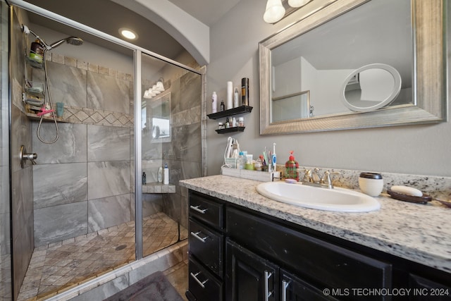 bathroom featuring a shower with door and vanity