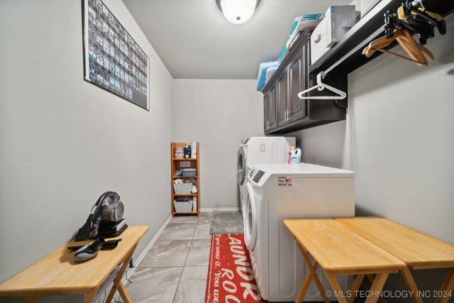 washroom with tile patterned flooring, cabinets, and washing machine and clothes dryer