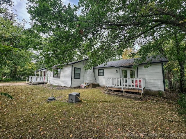 rear view of property with a wooden deck and a lawn