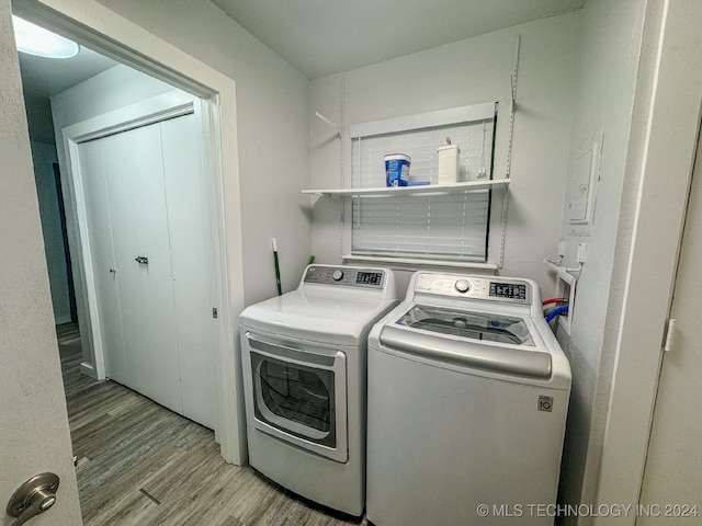 laundry room with separate washer and dryer and light hardwood / wood-style floors