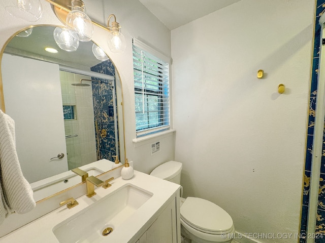 bathroom featuring toilet, a shower with door, and vanity