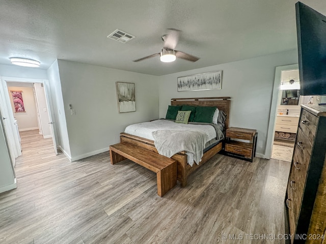 bedroom with a textured ceiling, ensuite bath, hardwood / wood-style floors, and ceiling fan