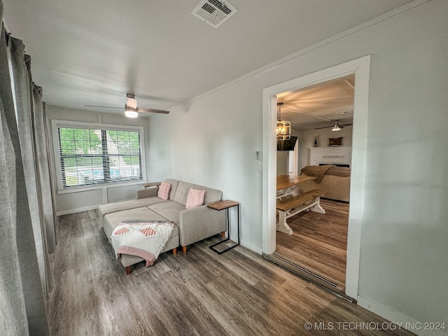 living room featuring ceiling fan, ornamental molding, a brick fireplace, and hardwood / wood-style flooring