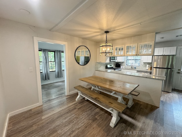 dining area featuring beamed ceiling, an inviting chandelier, sink, and dark hardwood / wood-style floors