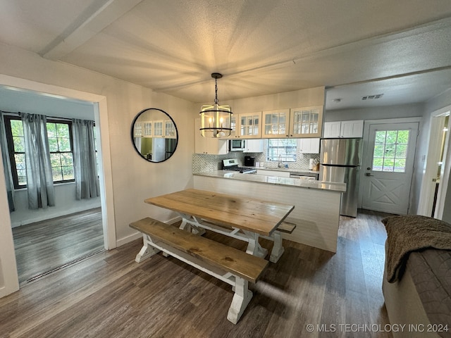 dining area with a chandelier, plenty of natural light, and dark hardwood / wood-style flooring