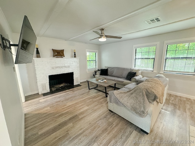 living room featuring ceiling fan, light wood-type flooring, and a fireplace