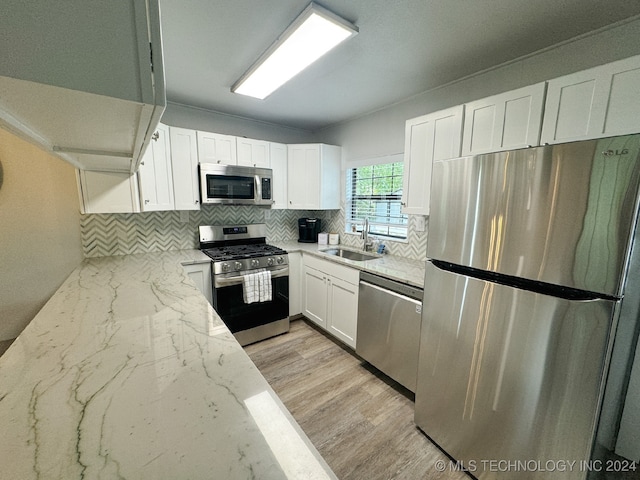 kitchen featuring white cabinetry, light hardwood / wood-style flooring, stainless steel appliances, light stone counters, and sink