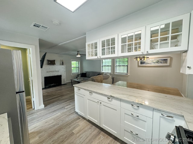 kitchen featuring light hardwood / wood-style flooring, light stone countertops, ceiling fan, appliances with stainless steel finishes, and white cabinets