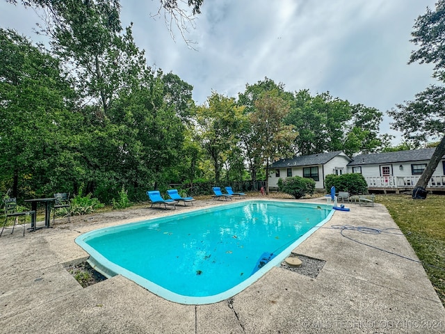 view of swimming pool featuring a wooden deck and a patio