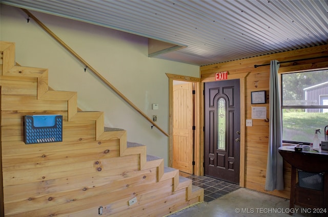 entryway featuring wood walls and concrete floors