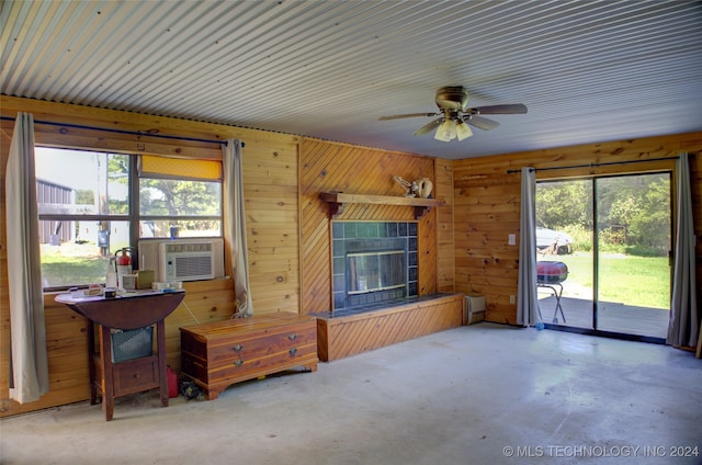 interior space featuring wood walls, concrete floors, ceiling fan, and cooling unit