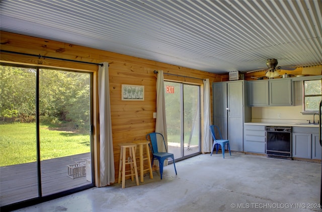 interior space with ceiling fan, plenty of natural light, and wooden walls