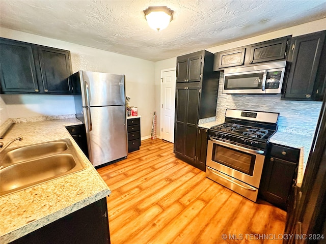 kitchen featuring sink, stainless steel appliances, light hardwood / wood-style floors, and tasteful backsplash