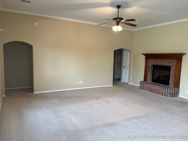 unfurnished living room with arched walkways, a fireplace, a ceiling fan, baseboards, and ornamental molding