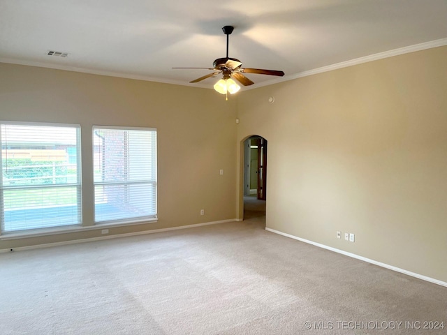 unfurnished room with baseboards, arched walkways, a ceiling fan, ornamental molding, and carpet flooring