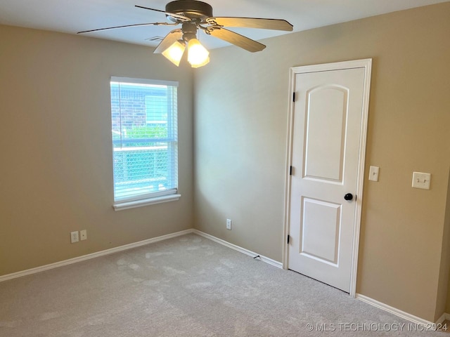 carpeted spare room featuring a ceiling fan and baseboards