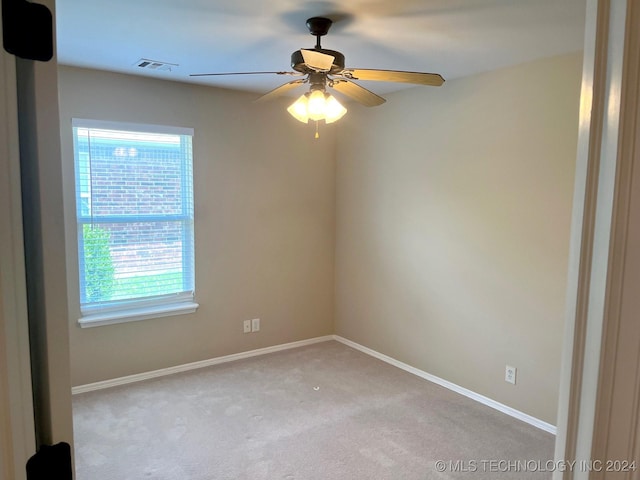 carpeted spare room with a ceiling fan, visible vents, and baseboards