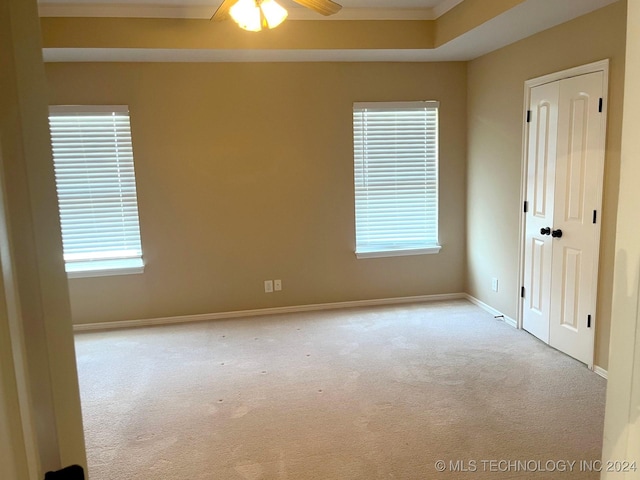 spare room with a raised ceiling, carpet flooring, ceiling fan, and baseboards