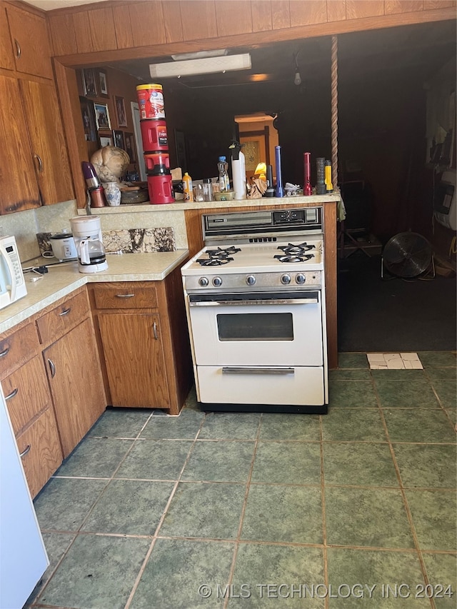 kitchen featuring dark tile patterned flooring and white gas stove