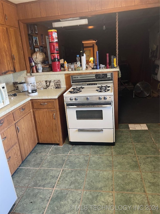 kitchen with brown cabinets, white appliances, light countertops, and a peninsula